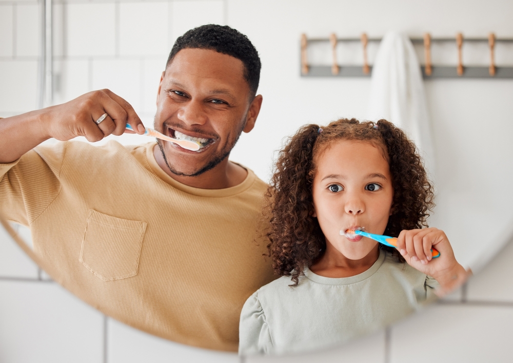 man and daughter brushing their teeth