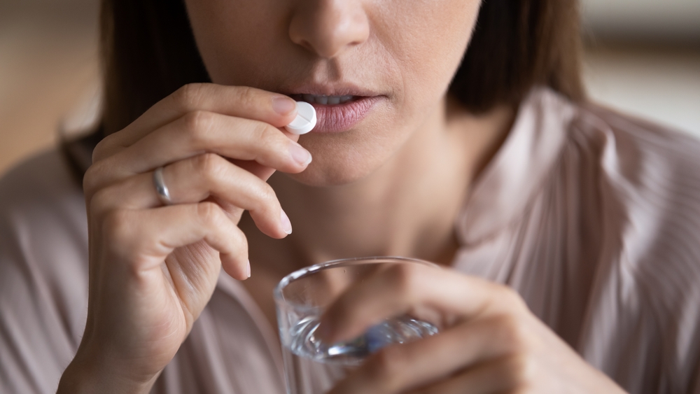 Close,Up,Sick,Woman,Holds,Glass,Of,Water,Takes,Pill woman taking pill
